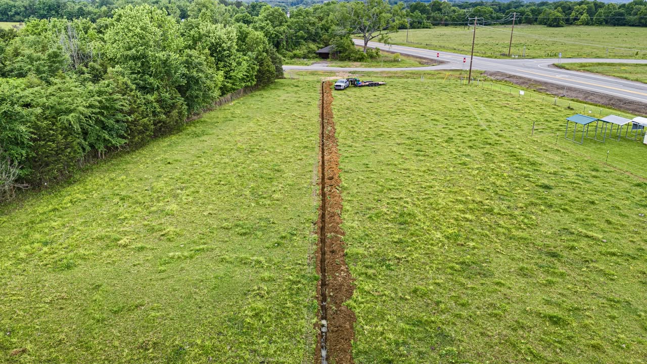 Long straight utility trench cut across a field